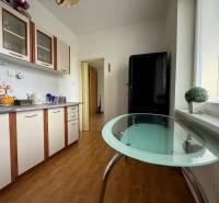 Küche in einer 2-Zimmer-Wohnung mit einem Glastisch und weißen Schränken.
