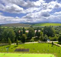 Blick aus einer 2-Zimmer-Wohnung im Westen von Tvrdošín, mit Spielplatz und hügeliger Landschaft.