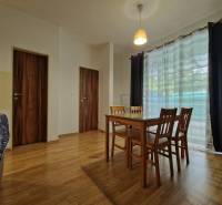 Esszimmer in einer Einzimmerwohnung mit Holzmöbeln und Glastüren.