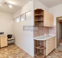 Küche in einer 3-Zimmer-Wohnung mit Mikrowelle, Stuhl und Schränken als Stauraum.