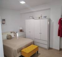 Helles Schlafzimmer in einer 2-Zimmer-Wohnung mit Kleiderschrank, Bett und bunten Möbeln.