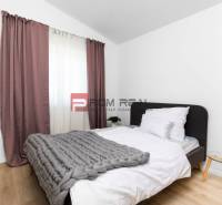 Schlafzimmer in einer 3-Zimmer-Wohnung mit Bett, grauer Decke und Nachttisch.