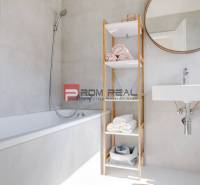 Badezimmer in einer 3-Zimmer-Wohnung mit Badewanne, offenem Regal und Spiegel an der Wand.