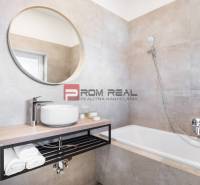 Badezimmer mit Waschbecken, Badewanne und rundem Spiegel in einer 3-Zimmer-Wohnung.