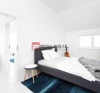 Ein Schlafzimmer mit Bett, blauem Teppich und Kleiderständer in einer 3-Zimmer-Wohnung.