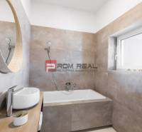 Ein Badezimmer mit Badewanne und Waschbecken in einer 3-Zimmer-Wohnung, Einfachheit und helle Töne.