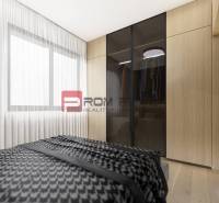 Schlafzimmer in einer 2-Zimmer-Wohnung mit einem Schrank und einem großen Fenster, helle Vorhänge.