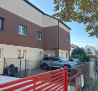 Zweistöckiges Wohnhaus in Bratislava - Ružinov, mit Parkplatz und rotem Zaun.