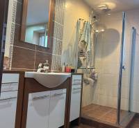 Badezimmer einer 2-Zimmer-Wohnung mit Dusche, Waschbecken und Schränken.