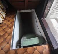Eine Treppe, die in den Keller der Hütte mit gefliestem Boden und geblümten Vorhängen führt.