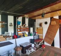 Interieur einer Hütte mit Küchenbereich, Wandregalen und Herd.