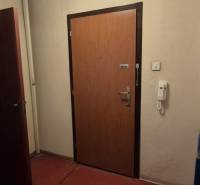 Eingangstür zu einer 3-Zimmer-Wohnung mit rotem Linoleum und weißen Wänden.