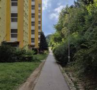 Gelbes Wohnhaus in der Moskauer Straße in Banská Bystrica neben dem Gehweg und dem Grün.