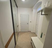 Heller Flur mit Fliesen, Einbauschrank und Bank in einer 2-Zimmer-Wohnung.