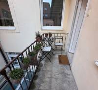 Ein schmaler Balkon mit Metallgeländer, Stühlen und Blumentöpfen in einer Zweizimmerwohnung.