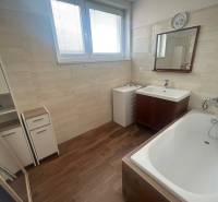 Badezimmer in einer 3-Zimmer-Wohnung mit Badewanne, Spiegel und Holzboden.