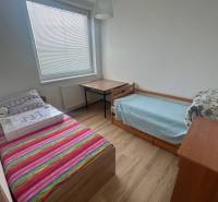 Ein Zimmer in einer 3-Zimmer-Wohnung mit zwei Betten, einem Tisch und Holzboden.