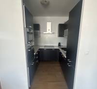 Küche in einer 3-Zimmer-Wohnung mit dunklen Schränken und eingebauten Geräten.