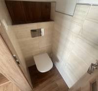 Toilette mit hellen Fliesen und Holzelementen in einer 3-Zimmer-Wohnung.