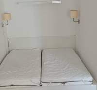 Ehebett mit Lampen an der Wand in einer 2-Zimmer-Wohnung.