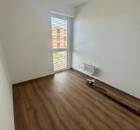 Ein leerer Raum mit Laminatboden und einem großen Fenster in einer 3-Zimmer-Wohnung.