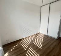 Ein leeres Zimmer in einer 3-Zimmer-Wohnung mit Holzboden und Einbauschrank.