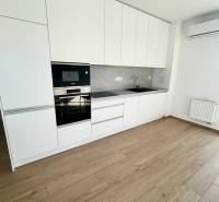Küche in einer 3-Zimmer-Wohnung mit weißen Schränken, Geräten und Holzboden.