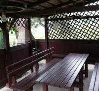 Ein hölzerner Pavillon mit Bänken im Garten eines Einfamilienhauses.