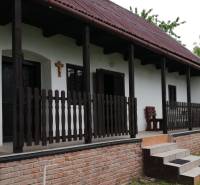 Ein Einfamilienhaus mit Terrasse, Holzzaun und Ziegelgrundlage in einer natürlichen Umgebung.