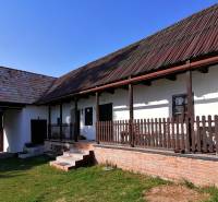 Ein Einfamilienhaus mit Veranda, Holzbalken, Ziegelgrundlage und einem großen Rasen im Garten.