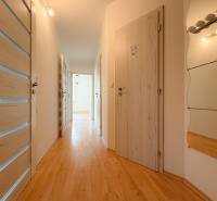 Der Flur in einer 3-Zimmer-Wohnung mit Holzboden, weißen Türen und einem Spiegel.