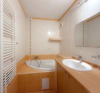 Badezimmer in einer 3-Zimmer-Wohnung mit Eckbadewanne, Waschbecken und Heizkörper.
