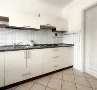 Eine Küchenzeile mit weißen Türen und einer schwarzen Arbeitsplatte in einer 3-Zimmer-Wohnung.