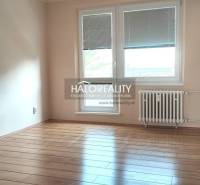 Ein Zimmer mit Holzboden in einer 4-Zimmer-Wohnung, ausgestattet mit einem Heizkörper und Fenstern mit Jalousien.