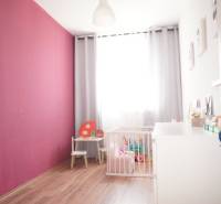 Kinderzimmer in einem Einfamilienhaus mit rosa Wand, Spielzeug und Kinderbett.