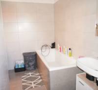 Ein Badezimmer in einem Einfamilienhaus mit einer Badewanne, einem Waschbecken und Aufbewahrungskörben für Wäsche.