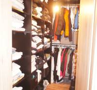 Ein Kleiderschrank mit Regalen und Kleiderbügeln voller Kleidung in einem Einfamilienhaus.
