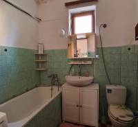 Ein Badezimmer in einem Einfamilienhaus mit Badewanne, Waschbecken und Toilette, grüne Fliesen.