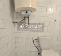 Ein Badezimmer in einem Einfamilienhaus mit Toilette und Boiler, gefliest mit weißen Fliesen.
