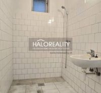 Badezimmer in einem Einfamilienhaus mit weißen Fliesen und Dusche.