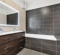Badezimmer mit Doppelwaschbecken, Badewanne und grauen Fliesen in der Vukovarská-Straße in einer 3-Zimmer-Wohnung.