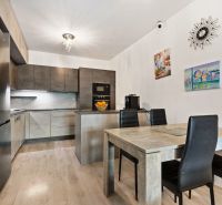 Küche in einer 3-Zimmer-Wohnung in der Vukovarská-Straße; graue Schränke, Esstisch, Dekorationen.