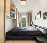 Schlafzimmer mit Bett, Einbauschrank und Blick in den Garten. Geeignet für eine 3-Zimmer-Wohnung in der Vukovarská-Straße.