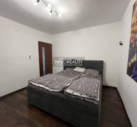 Schlafzimmer in einem Einfamilienhaus mit Bett, dunklem Boden und Bild an der Wand.