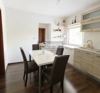 Esszimmer in einem Einfamilienhaus mit weißem Tisch, braunen Stühlen und einem Boden in Holzoptik.