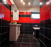 Schwarz-rotes Badezimmer in einem Einfamilienhaus mit Spiegel und Badewanne, auffällige Kombination von Fliesen.