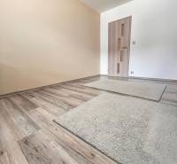 Ein Raum in einem Einfamilienhaus mit einem Boden in Holzoptik und hellen Wänden.