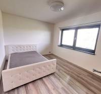 Schlafzimmer im Einfamilienhaus mit Bett und Boden in Holzoptik.