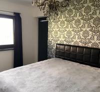 Schlafzimmer im Einfamilienhaus mit dekorativer Tapete und Kronleuchter. Symphonie des Innendesigns.