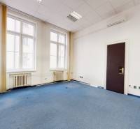 Ein Bürointerieur mit blauem Teppich, weißen Wänden und großen Fenstern.